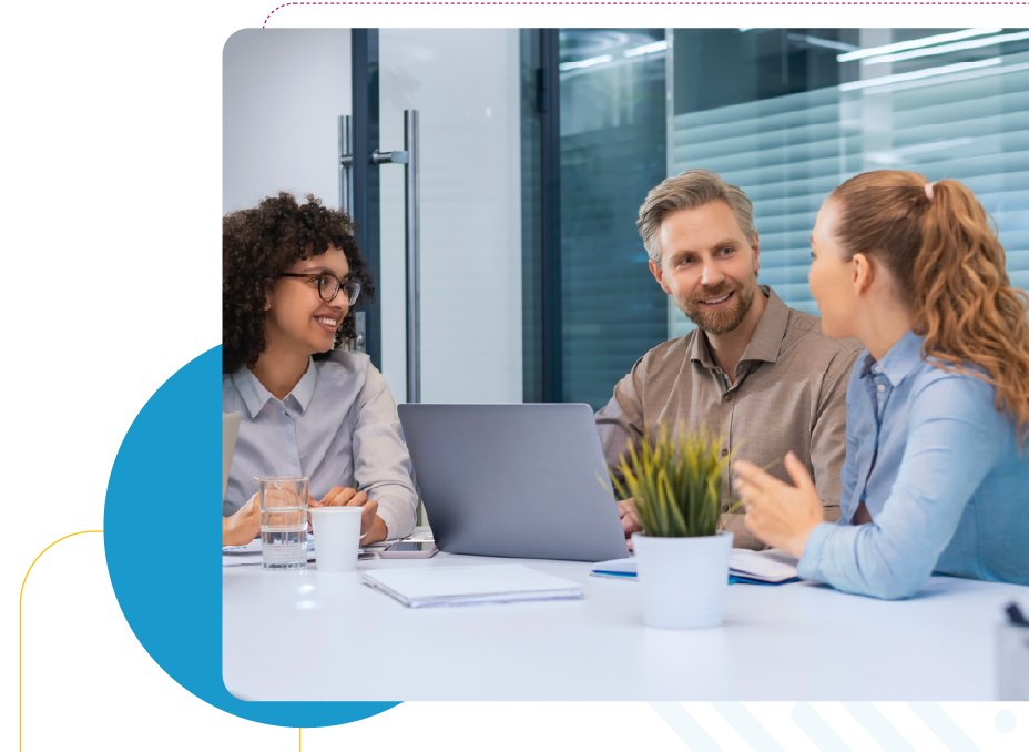 Three people in business attire sitting at a table talking to eachother.