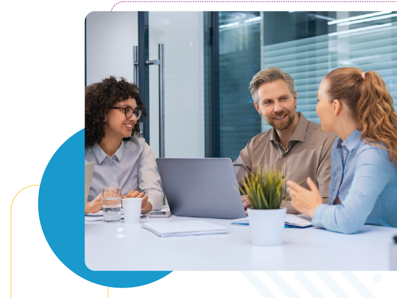 Three people in business attire sitting at a table talking to eachother.